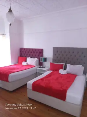 two beds in a bedroom with red and white at Neo & ruks guest houses Boston Belleville 4 in Bellville