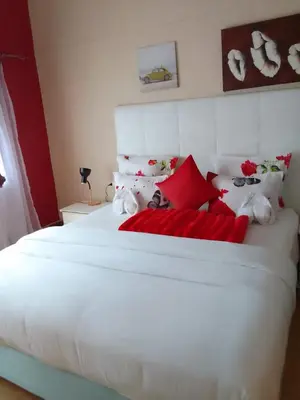 a bedroom with a large white bed with red pillows at Neo & ruks guest houses Boston Belleville 4 in Bellville