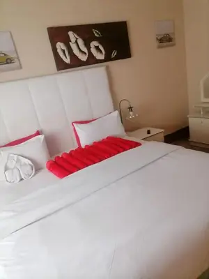 a bedroom with a large white bed with red pillows at Neo & ruks guest houses Boston Belleville 4 in Bellville
