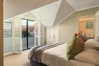 a bedroom with a bed and a large window at Pearl Valley family golf lodge on nature lake with mountain views in Simondium