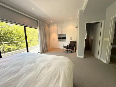a bedroom with a large white bed and a balcony at Pearl Valley family golf lodge on nature lake with mountain views in Simondium