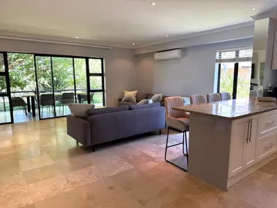 a living room with a couch and a table at Pearl Valley family golf lodge on nature lake with mountain views in Simondium