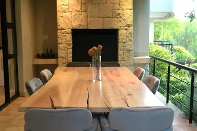 a wooden table with chairs and a vase with flowers at Pearl Valley family golf lodge on nature lake with mountain views in Simondium