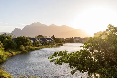 a river with houses and mountains in the background at Pearl Valley family golf lodge on nature lake with mountain views in Simondium