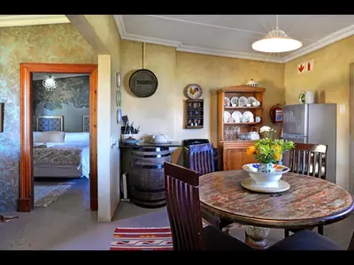 a kitchen and dining room with a table and a bedroom at Courchevel Cottages in Franschhoek