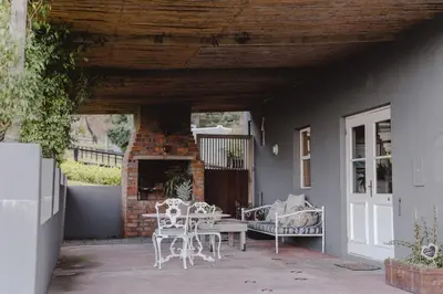 a patio with chairs and a table and a fireplace at Courchevel Cottages in Franschhoek