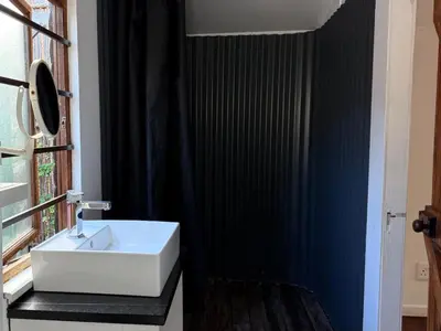 a bathroom with a white sink and a black wall at Surfers Lodge in Cape Town