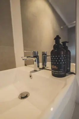 a soap dispenser sitting on a bathroom sink at Surfers Lodge in Cape Town