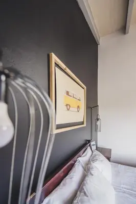 a picture of a van on a wall above a bed at Surfers Lodge in Cape Town