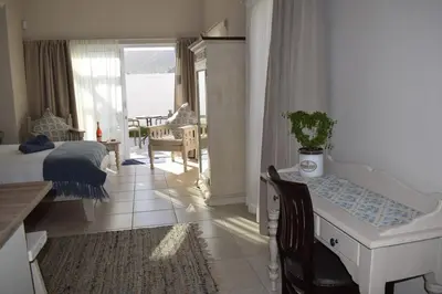 a bedroom with a bed and a living room with a table at PROVIDENCE VILLA -Tranquil, Neat & Private Cottage in Hermanus