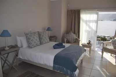 a bedroom with a bed with a blue blanket on it at PROVIDENCE VILLA -Tranquil, Neat & Private Cottage in Hermanus