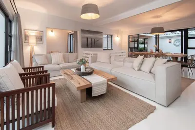 a living room with a white couch and a table at Fun in the Voelklip Sun in Hermanus