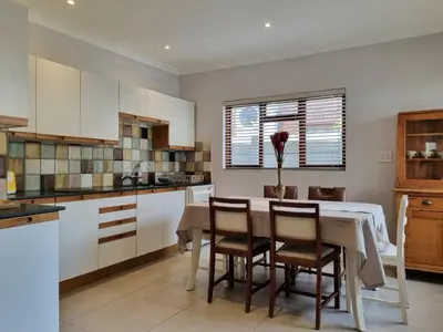 a kitchen with a table and some chairs and a table and a kitchen at 'Country Beach House' - Traditional Family Vacation Home for 6 - Near Beach in Gordonʼs Bay