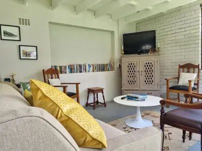 a living room with a couch and a tv at 'Country Beach House' - Traditional Family Vacation Home for 6 - Near Beach in Gordonʼs Bay