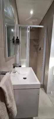 a bathroom with a white sink and a shower at Sound of the surf in Cape Town
