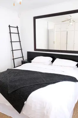 a bedroom with a large mirror above a bed at Villa on Flamingo Vlei in Cape Town