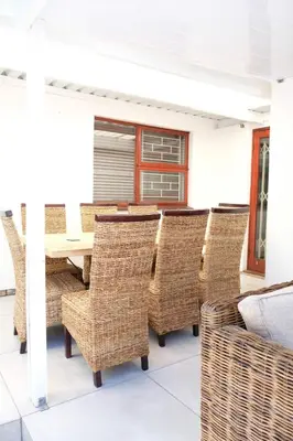 a dining room with wicker chairs and a table at Villa on Flamingo Vlei in Cape Town