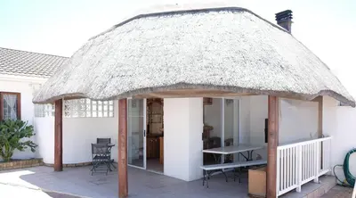 a thatch roofed gazebo outside of a house at Villa on Flamingo Vlei in Cape Town