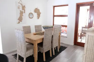 a dining room with a wooden table and chairs at Villa on Flamingo Vlei in Cape Town