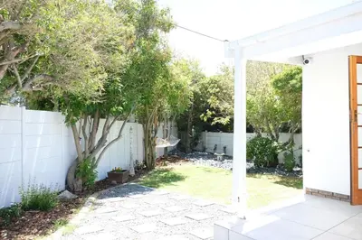 a backyard with a white fence and a tree at Villa on Flamingo Vlei in Cape Town