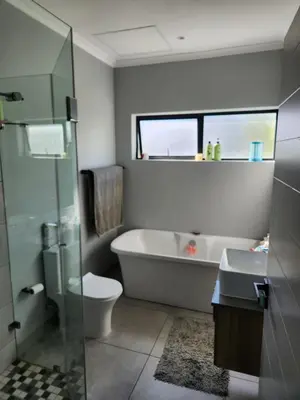 a bathroom with a tub and a toilet and a sink at St James home in Somerset West