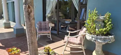a porch with two chairs and a table and a window at Arendsnest Self Catering in Gordonʼs Bay