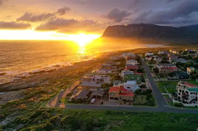 an aerial view of a small town near the ocean at sunset at La Mer Seafront Selfcatering Accommodation Kleinmond in Kleinmond