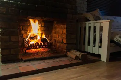 a brick fireplace with a fire in it at La Mer Seafront Selfcatering Accommodation Kleinmond in Kleinmond