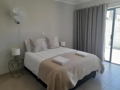 a white bedroom with a bed with two towels on it at Cornerstone Guesthouse Drostdy in Panorama