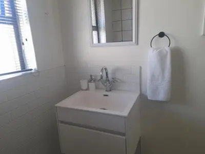 a white bathroom with a sink and a mirror at Cornerstone Guesthouse Drostdy in Panorama