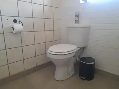 a bathroom with a toilet and a trash can at Cornerstone Guesthouse Drostdy in Panorama
