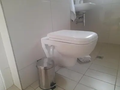 a bathroom with a toilet and a trash can at Cornerstone Guesthouse Drostdy in Panorama