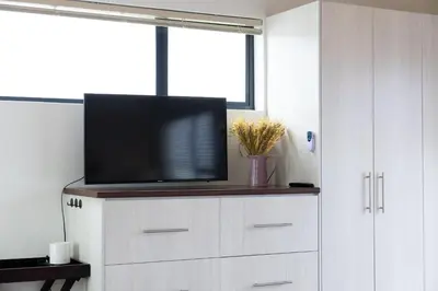 a tv on top of a white cabinet in a room at Studio 98 - 300m from cliff path in Hermanus