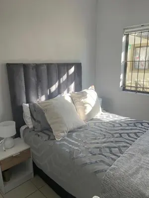 a bed with pillows on it in a bedroom at Beautiful 2 bedroom apartment in strand in Somerset West