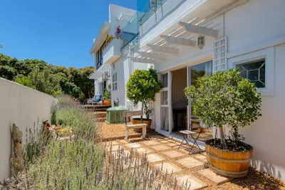 a patio of a house with chairs and trees at Whale Watchers Gordons Bay in Gordonʼs Bay