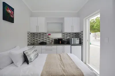 a white kitchen with a bed in a room at Leetch Views - Budget Room in Cape Town