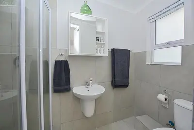 a white bathroom with a sink and a shower at Leetch Views - Budget Room in Cape Town