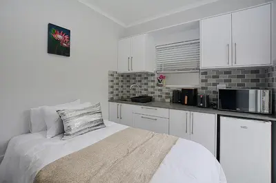 a white kitchen with a bed and a microwave at Leetch Views - Budget Room in Cape Town