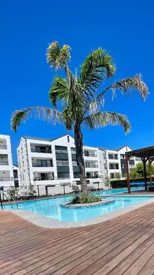 a palm tree in front of a large building at Altin Pearl Luxury Apartment in Cape Town