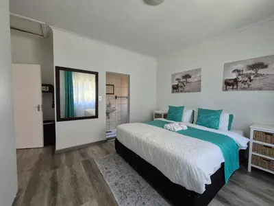 a bedroom with a large bed with blue pillows at ESME's REST in Cape Town