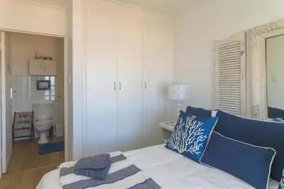 a bedroom with a bed with blue and white pillows at Oceanfront Escape with Spacious Balcony Hermanus in Hermanus