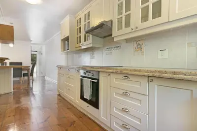 a large kitchen with white cabinets and a wooden floor at Gordonia 10 in Cape Town