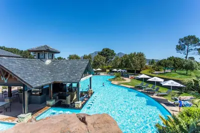 a pool at a resort with chairs and umbrellas at Luxury Lodge 5B, Pearl Valley Golf Estate in Simondium