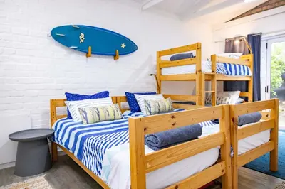 a bedroom with two bunk beds and a surfboard on the wall at Onrus Island Milkwood Sanctuary in Hermanus
