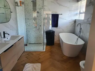 a bathroom with a tub and a shower and a sink at Classy 3 storey house in Gordonʼs Bay