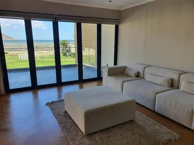 a living room with a couch and a ottoman at Classy 3 storey house in Gordonʼs Bay