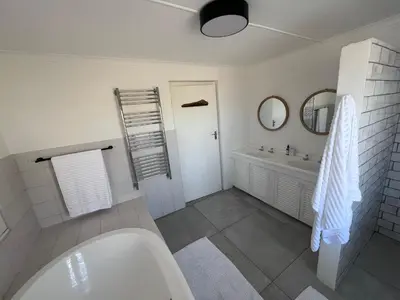 a white bathroom with a tub and a sink at Unique views Betties Bay in Bettyʼs Bay