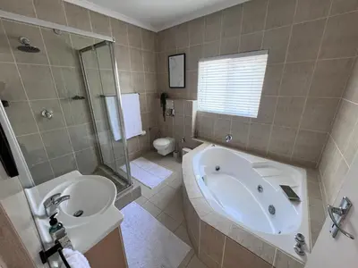 a bathroom with a tub and a sink and a toilet at Unique views Betties Bay in Bettyʼs Bay