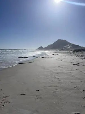 a beach with a surfboard sitting on the sand at Unique views Betties Bay in Bettyʼs Bay