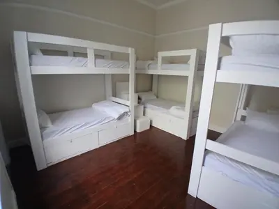 two white bunk beds in a room with wooden floors at Star legend backpackers - Parow in Parow